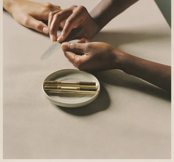 A nail technician shaping a client's nail with a fine file